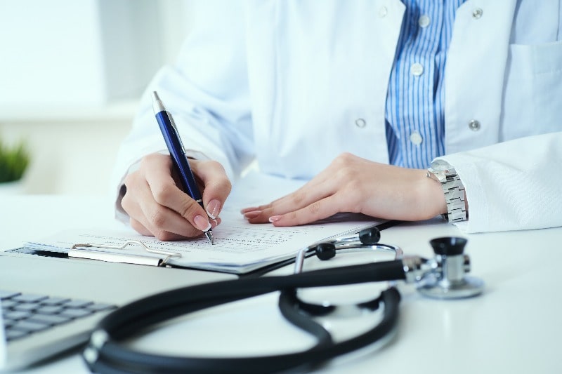 Doctor writing notes on clipboard