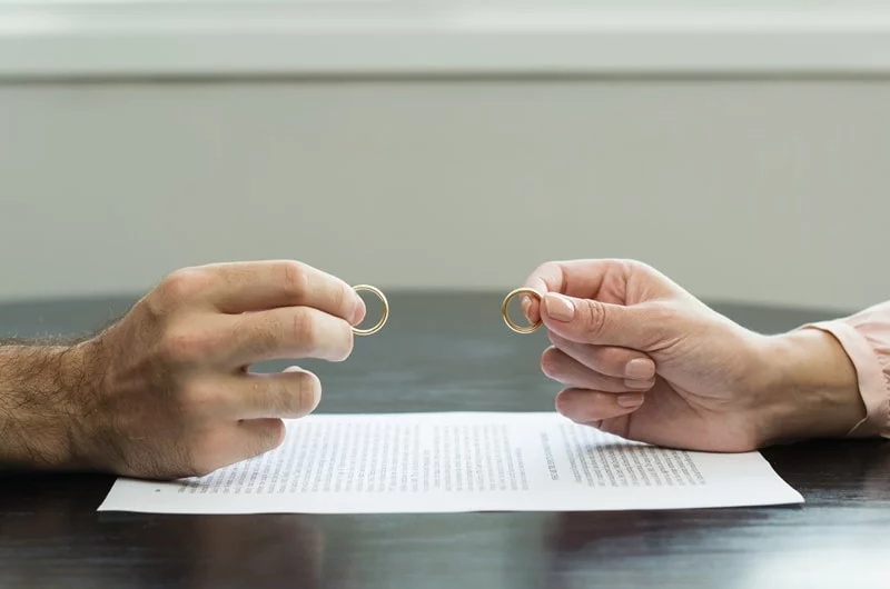 couple holding rings up in front of document