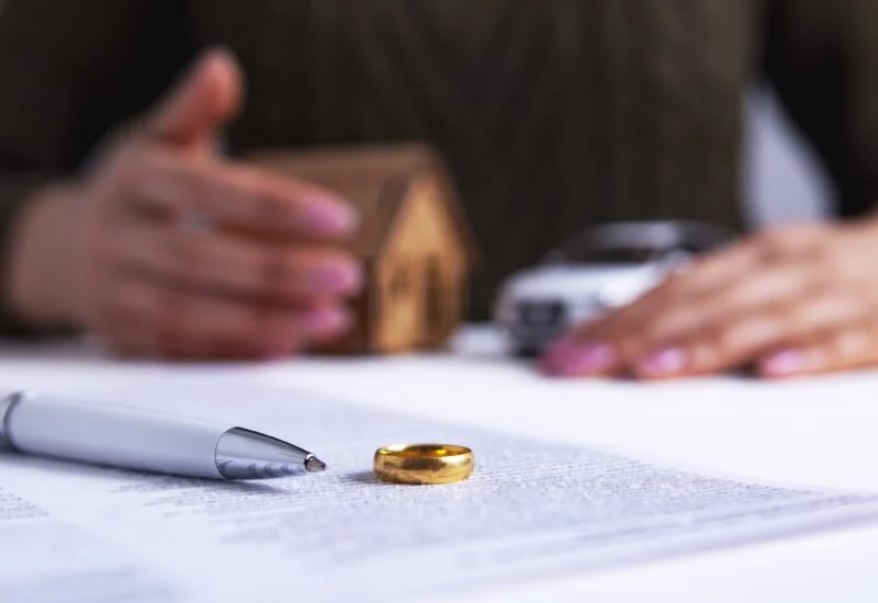 Ring on paper with pen and women holding small model of house and car