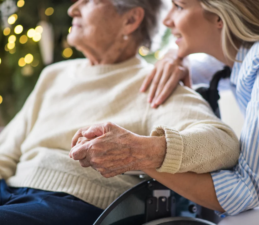 women holding grandmothers hand in a wheelchair