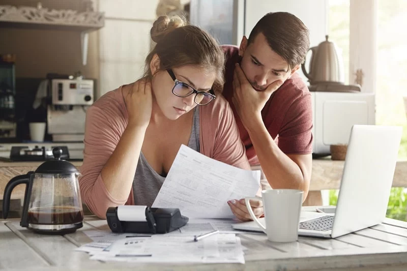 Couple, man and women looking over finance documents in house, looking stressed