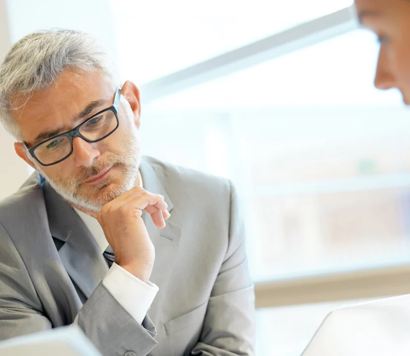 Man and women looking over document. Man looking focused and thinking