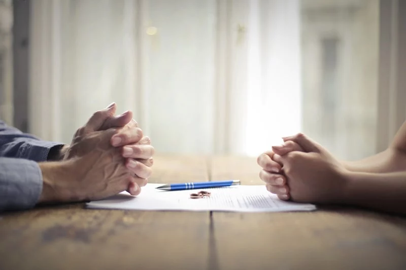 Man and women sitting opposite each other with documents and pen in the middle of them