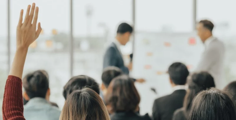 two men presenting and a hand up to ask a question