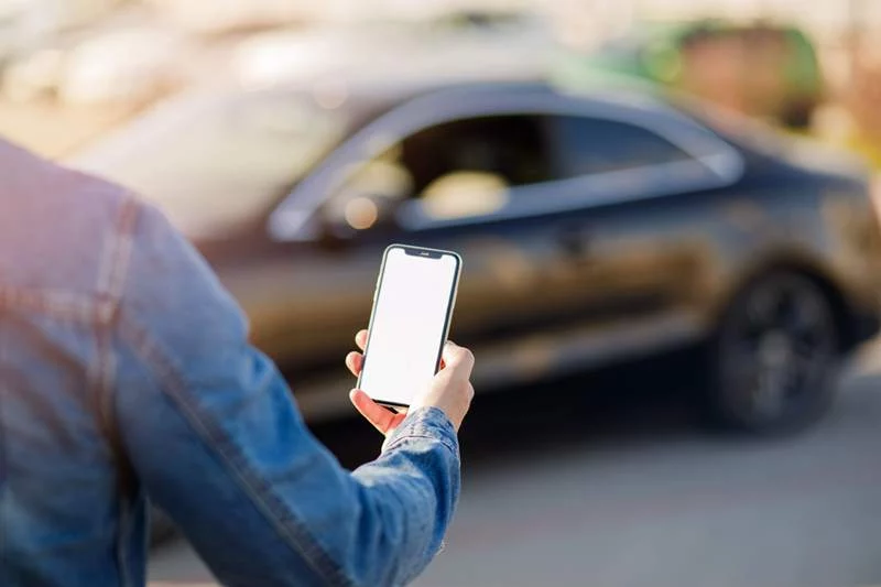 Person holding up phone, in front of the car