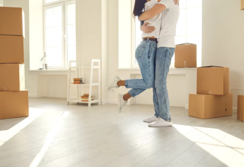 Man and women moving out and hugging in new house with boxes
