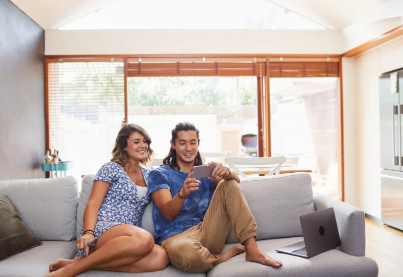 Couple looking at phone together on their sofa in their house