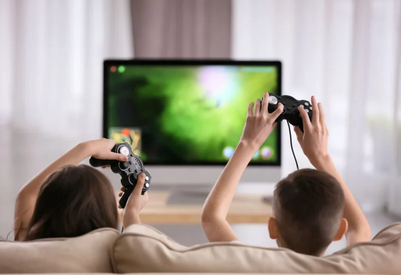 Kids playing video games on monitor and sofa