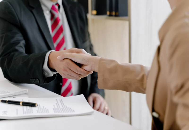 Man and women shaking hands over document