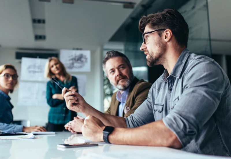 Group of people having a meeting, focusing on a a man pointing