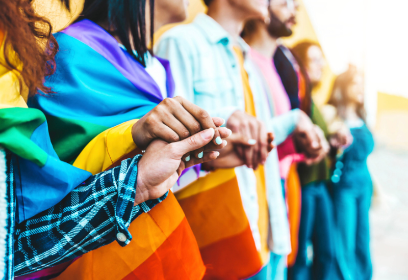 LGBT flag being held in a row of people