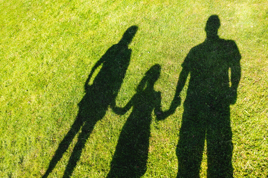 Shadow of family holding hands together at a park