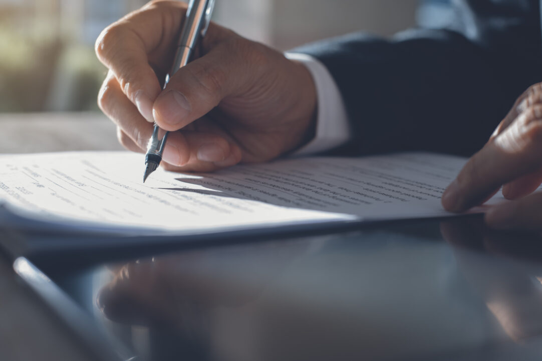 Business man in black suit signing contract document