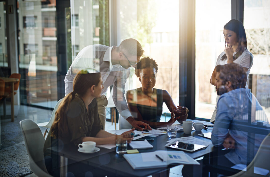 group of five business people having a meeting in a boardroom with paperwork