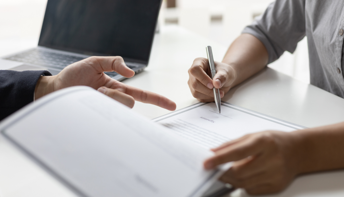 two people looking over document and one signing