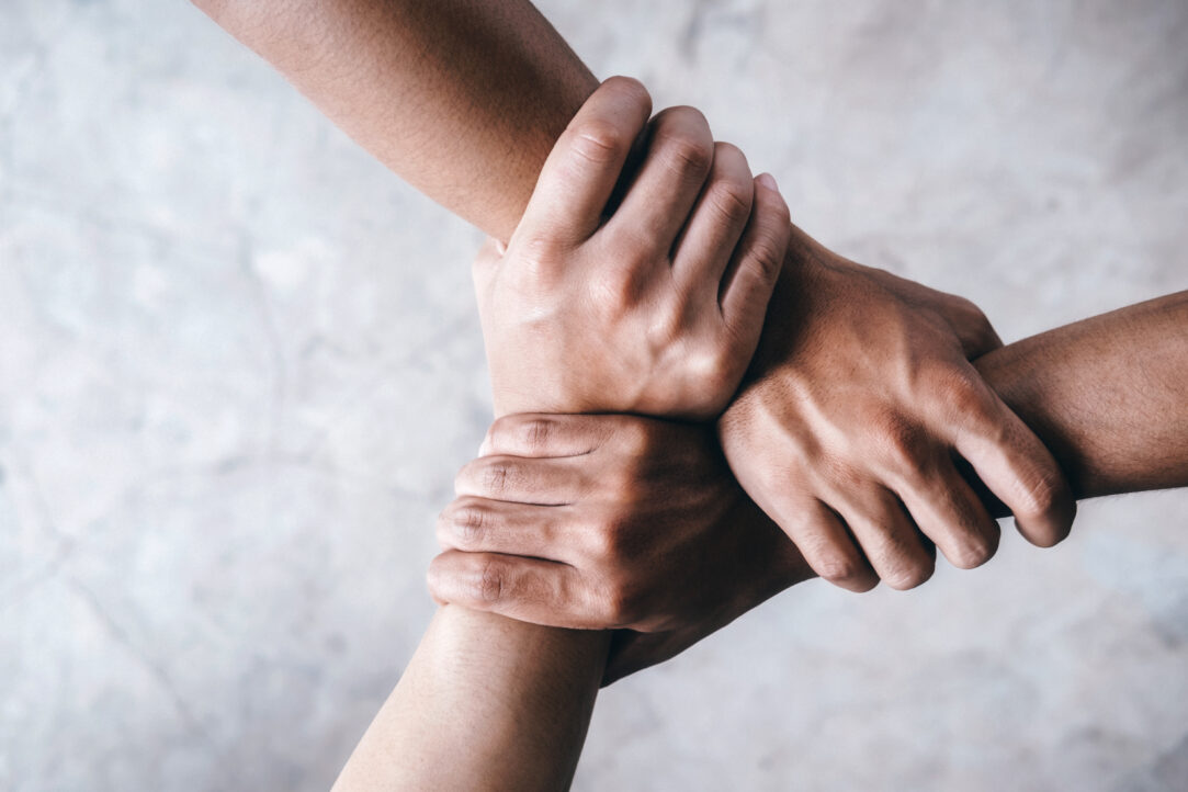 Close up top view of young people putting their hands together showing unity and teamwork.